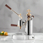 La Pavoni Expo 2015 Coffee Machine featuring a chrome-plated body with gold accents, wooden handles, and lever mechanism. Professional-grade espresso maker with drip tray and elegant eagle finial displayed on grey marble countertop.